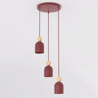 Bordeauxrode hanglamp met drie capsulevormige kappen aan een ronde plafondplaat, met houten accenten op de snoeren