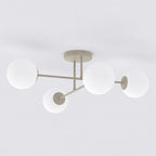 Beige plafondlamp met vier armen en witte glazen bollen tegen een lichte achtergrond
