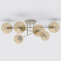 Beige plafondlamp met zes armen en amberkleurige glazen bollen tegen een lichte achtergrond