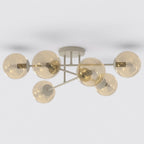 Beige plafondlamp met zes armen en amberkleurige glazen bollen tegen een lichte achtergrond