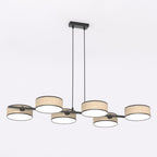 Lineaire hanglamp met zes cilindervormige rotan kappen aan een zwart stalen frame, opgehangen aan twee dunne stangen