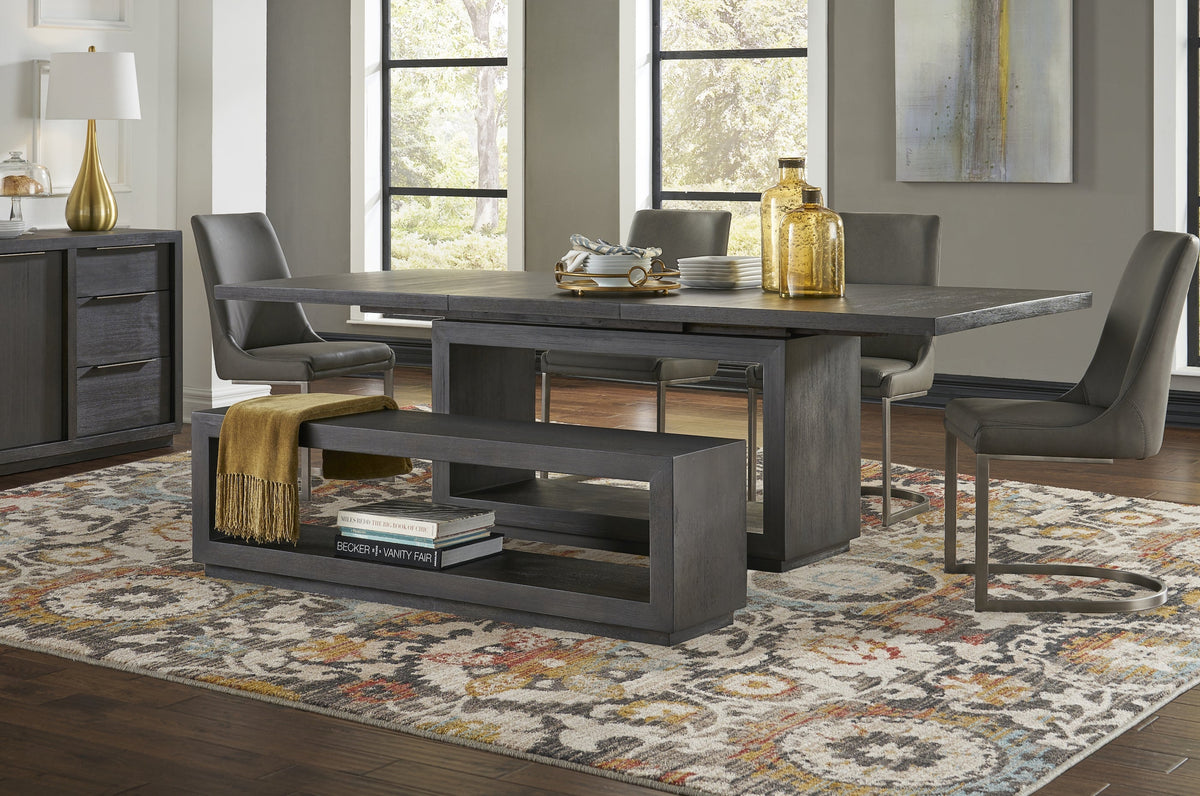 Rechthoekige donkergrijze eettafel met grijze stoelen, een open bankje en een gekleurd vloerkleed in een eetkamer