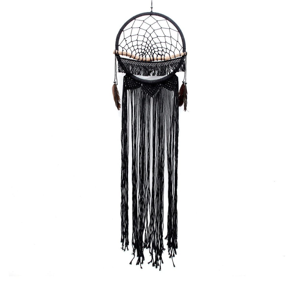 Zwarte macramé dromenvanger met houten stok, veren en lange franjes aan de muur