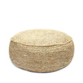 Ronde gevlochten poef van naturel raffia op een witte achtergrond