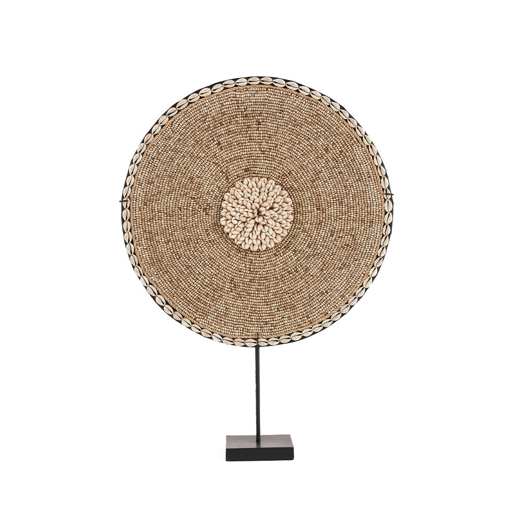 Rond decoratieobject met kralen en schelpen in naturel tinten op een zwarte standaard met vierkante voet