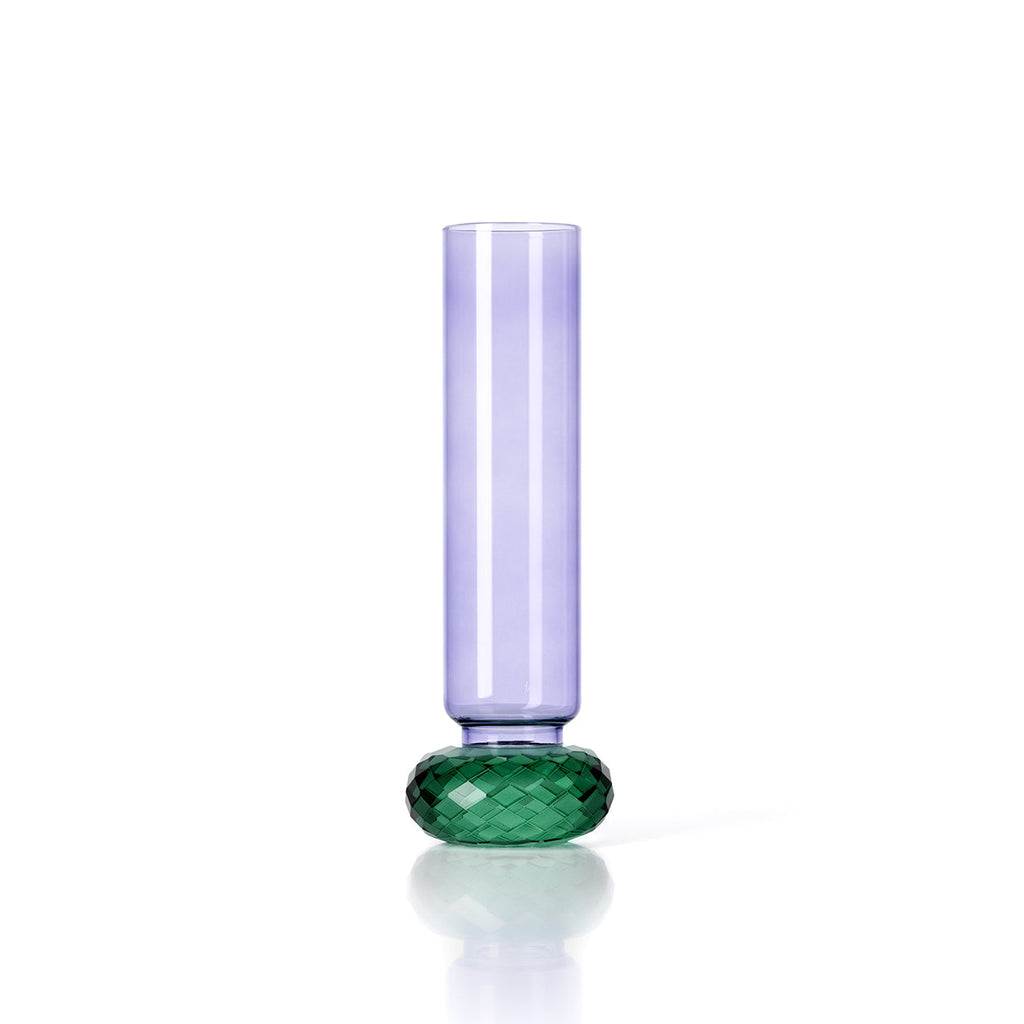 Slanke vaas van paars glas op een geslepen groene glazen voet, tegen een witte achtergrond