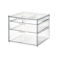 Transparante make-up organizer met drie lades met witte handgrepen en een tray bovenop