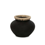 Bolle zwarte terracotta vaas met een rand van naturel raffia op een witte achtergrond