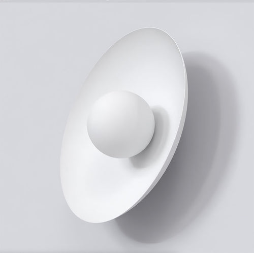 Witte wandlamp met ovale rugplaat en ronde witte bol aan een lichtgrijze wand