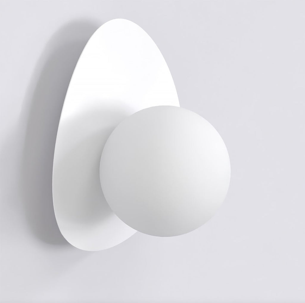 Witte wandlamp met ronde bol op een keivormige witte achterplaat tegen een lichte muur