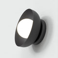 Zwarte wandlamp met gewelfd frame en verlichte witte bol aan een lichte wand