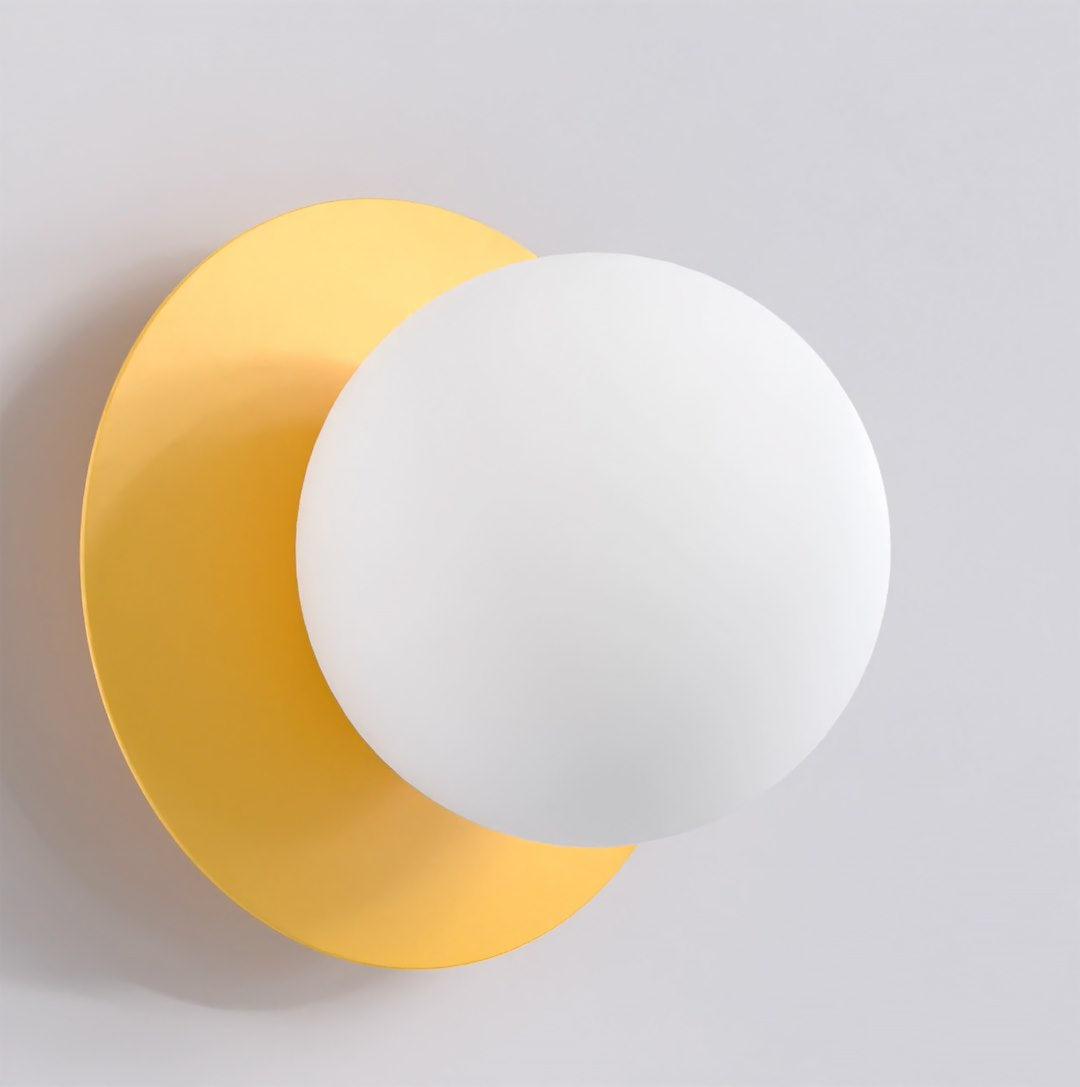 Wandlamp met matte witte bol voor een ronde oranje achterplaat tegen een lichte muur