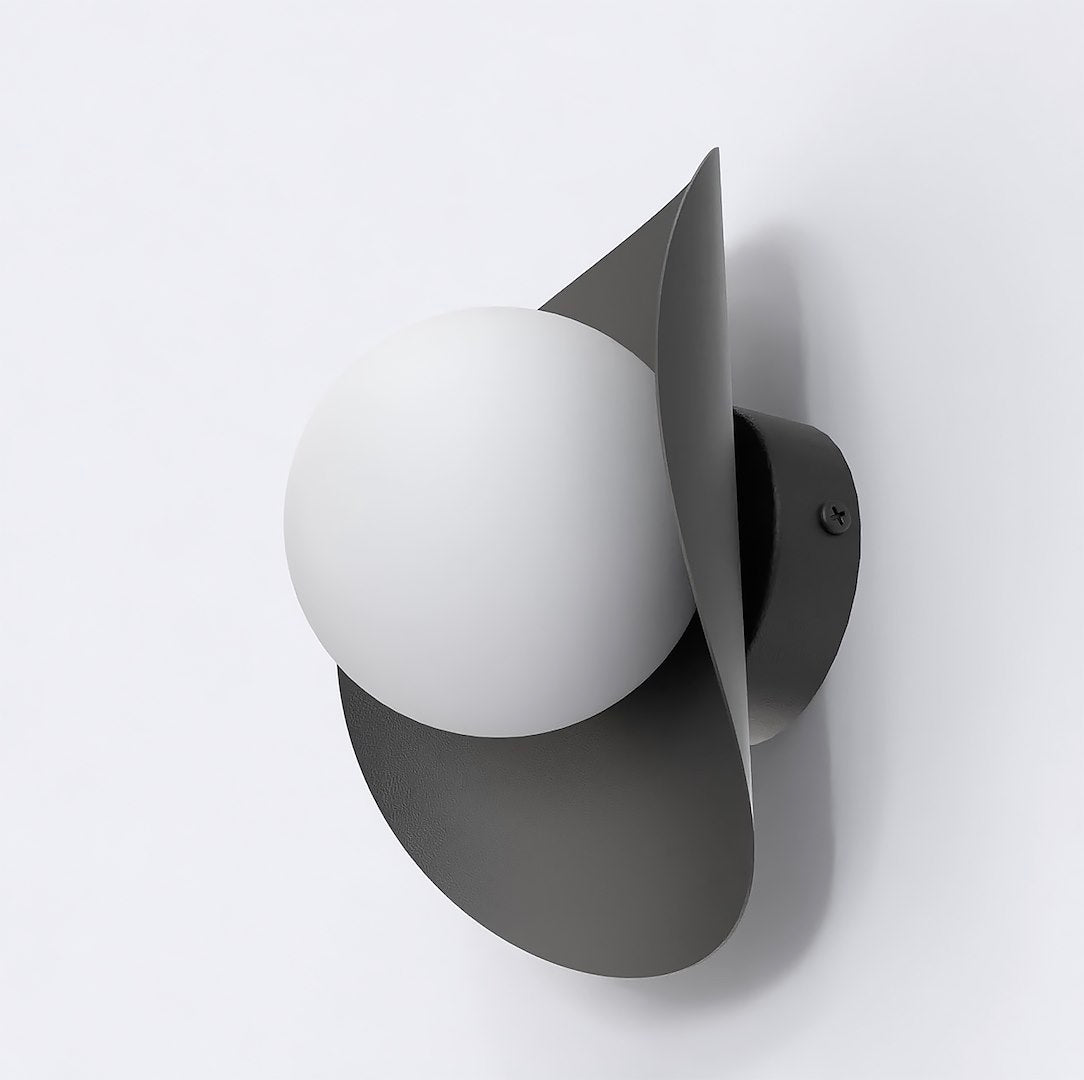 Zwarte wandlamp met lintvormige metalen kap en een witte bol aan een lichte wand