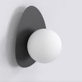 Zwarte wandlamp met kiezelvormige stalen achterplaat en ronde witte bol als kap