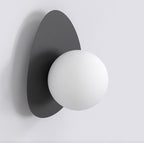 Zwarte wandlamp met kiezelvormige stalen achterplaat en ronde witte bol als kap