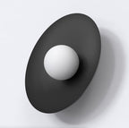 Zwarte ovale wandlamp met ronde witte kap tegen een lichte wand