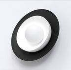 Zwarte ovale wandlamp met een witte schaal en een witte bol in het midden
