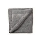 Opgevouwen grijze badstof badhanddoek met gestreepte band langs de rand