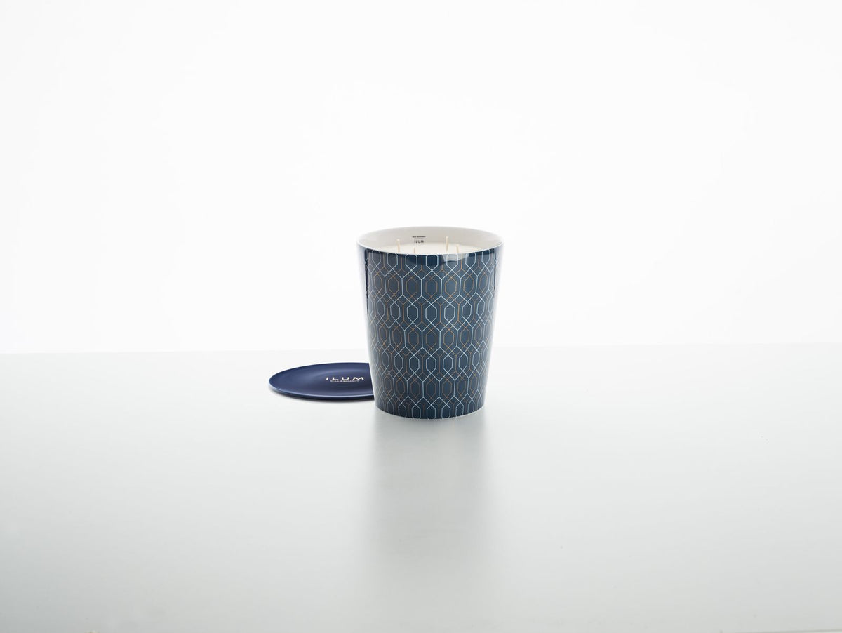 Donkerblauwe geurkaars in pot met grafisch patroon, met een blauw schoteltje ernaast op een lichte ondergrond