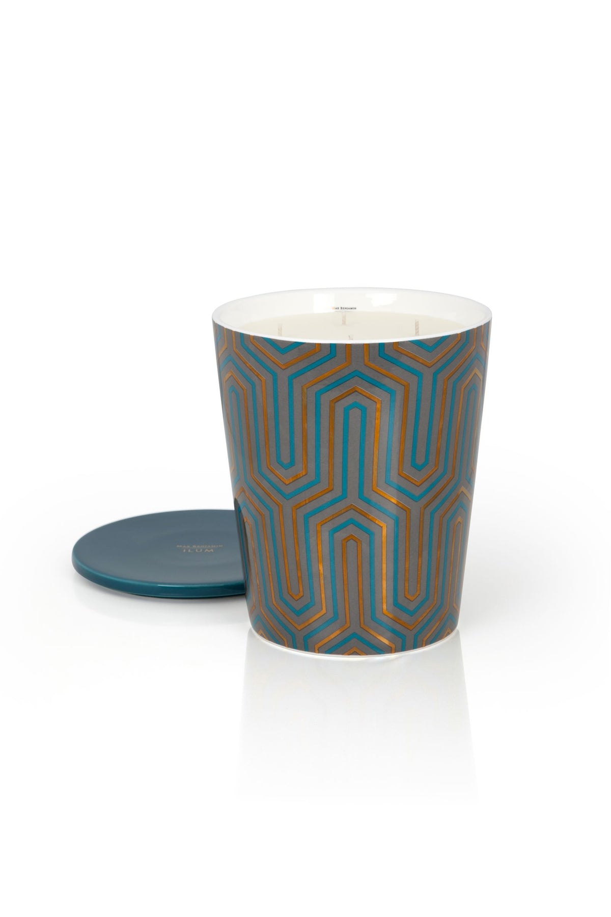 Decoratieve geurkaars met blauw-koperkleurig geometrisch patroon en los blauw deksel naast de kaars