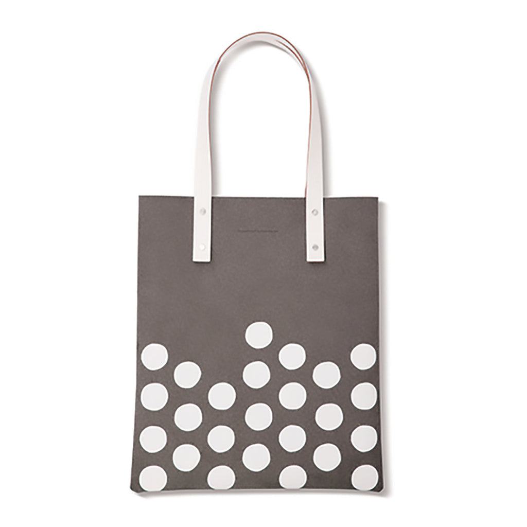 Grijze totebag met witte stippen onderaan en twee lange witte hengsels met klinknagels