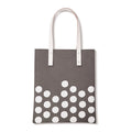 Grijze totebag met witte stippen onderaan en twee lange witte hengsels met klinknagels