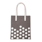 Grijze totebag met witte stippen onderaan en twee lange witte hengsels met klinknagels